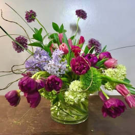 Purple and pink tulips with allium and hydrangea in a glass vase