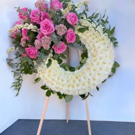 Heart-shaped floral wreath with pink roses and white chrysanthemums on an easel