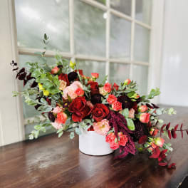 Mixed red and pink floral arrangement in a white vase