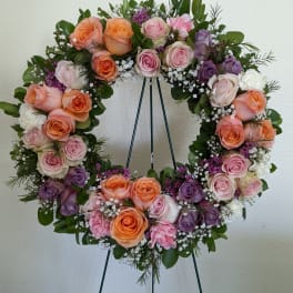 Circular wreath of pink, peach, and purple roses on a stand