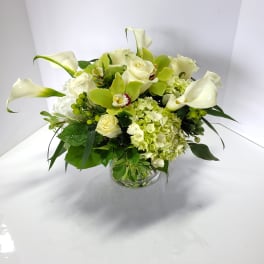 White calla lilies and roses arranged in a glass vase