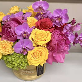 Bright bouquet of yellow and pink roses with purple orchids in a gold vase
