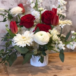Red and white mixed flower arrangement in a white vase