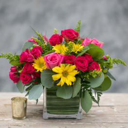 Pink roses and yellow daisies in a square glass vase