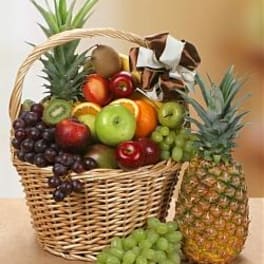 Fruit basket with grapes, apples, oranges, and pineapples in wicker containers
