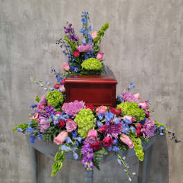Colorful floral arrangement surrounding a wooden urn on a table