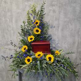 Sunflower funeral spray around a red urn on a pedestal