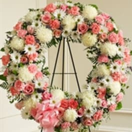 Pink and white floral wreath on a black easel with a pink ribbon