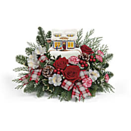 Christmas floral arrangement with red roses and a small house ornament