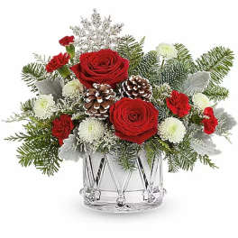 Red roses and white flowers in a clear glass vase with pinecones