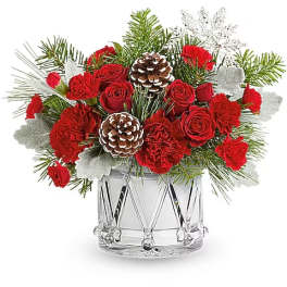 Red roses and carnations in a clear glass vase with pinecones and evergreen accents
