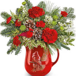 Red carnations and pinecones arranged in a red pitcher vase