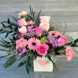 Pink mixed flower arrangement in a white box with a heart accent