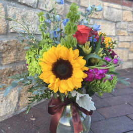 Mixed bouquet with a sunflower in a glass vase tied with a burgundy ribbon