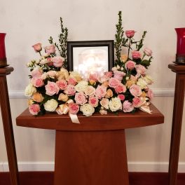 Pink and cream rose arrangement on a wooden memorial stand