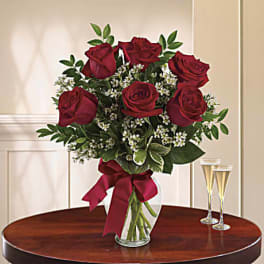 Bouquet of red roses in a glass vase with a burgundy ribbon