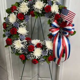 Red, white, and blue floral wreath on a stand with an American flag ribbon