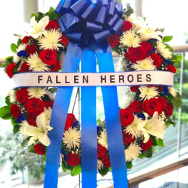 Red and white floral wreath with a blue ribbon and "FALLEN HEROES" banner