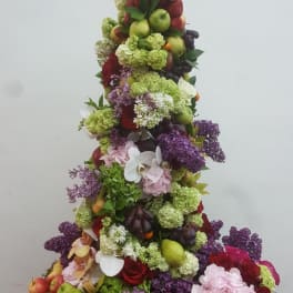 Tiered floral display with fruit, hydrangeas, roses, and orchids