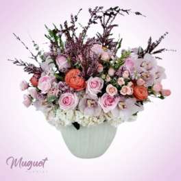 Pink and white rose arrangement in a pale vase