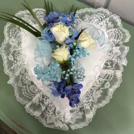 Heart-shaped bouquet of white roses and blue flowers with lace trim
