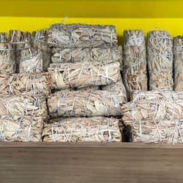 Bundles of dried sage or smudge sticks stacked on a shelf