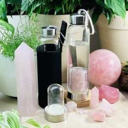 Crystal towers and pink stones arranged with glass water bottles and potted plants