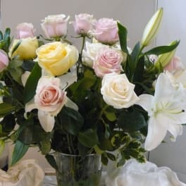 Bouquet of pink and white roses with white lilies in a glass vase