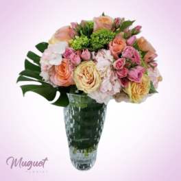 Mixed pink and peach roses in a tall glass vase