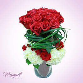 Red roses and white hydrangeas in a glass vase with looping green ribbon