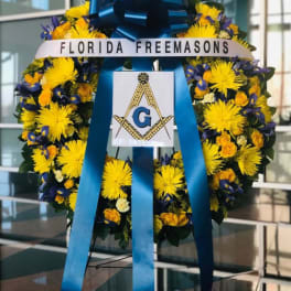 Large floral wreath with yellow and blue flowers and a blue ribbon bow