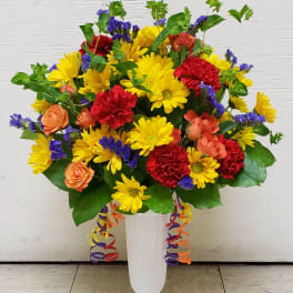 Bright mixed bouquet in a white pedestal vase with ribbon curls