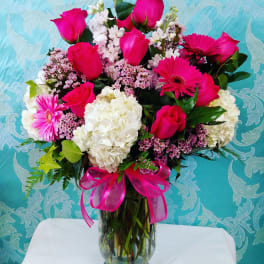 Bouquet of pink roses, gerbera daisies, and white hydrangeas in a glass vase