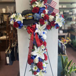 Floral standing cross with red, white, and blue flowers and small American flags