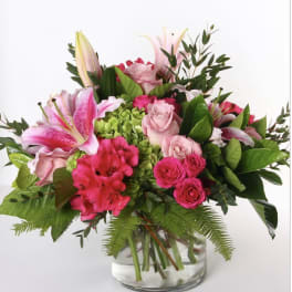 Pink lilies and roses arranged in a clear glass vase