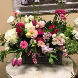 Mixed pink, white, and green floral arrangement in a rectangular container