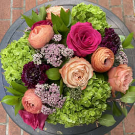 Bouquet of pink and peach roses with green hydrangeas and purple accents