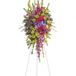 Tall standing floral spray with pink, purple, and yellow flowers on an easel