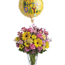 Birthday balloon above a mixed bouquet in a glass vase