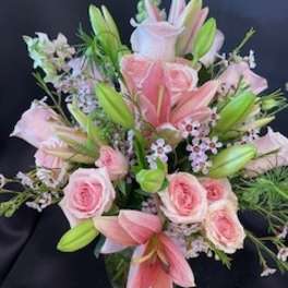 Pink lilies and roses arranged with small filler flowers