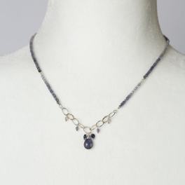 Purple beaded necklace with a dangling pendant on a white display bust