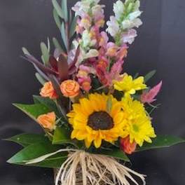 Bouquet with sunflowers, orange roses, and tall snapdragons in a basket