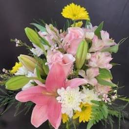 Pink lilies and roses with white daisies in a glass vase