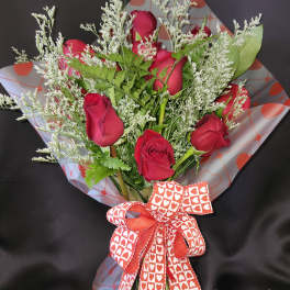 Bouquet of red roses with white filler and a heart-patterned ribbon