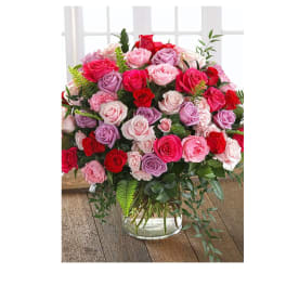 Mixed pink, red, and lavender roses in a clear glass vase