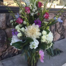 Tall mixed flower arrangement in a glass vase with pink, white, and purple blooms