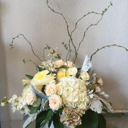 Cream and blush floral arrangement in a white vase with tall curly branches