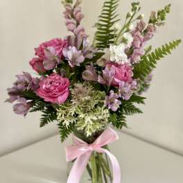 Pink and lavender bouquet in a glass vase with a pink ribbon
