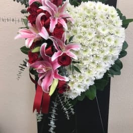 Heart-shaped floral spray with pink lilies, red roses, and white chrysanthemums