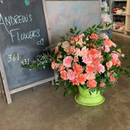 Large peach and pink carnation arrangement in a bright green vase